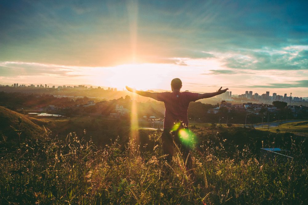 Man arms spread out in field